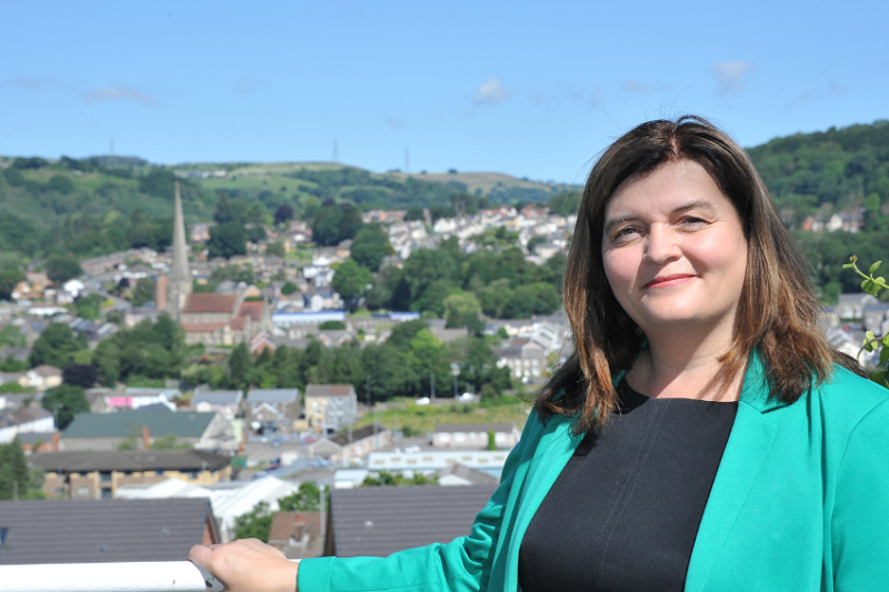 Sioned Williams yn tywodio gyda golygfa o Gwm Tawe yn y cefndir