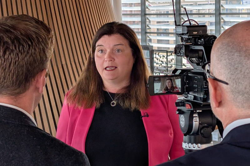 Sioned Williams MS yn cael ei chyfweld gan ddau ddyn â'u cefnau atom. Sioned o flaen camera yn y senedd