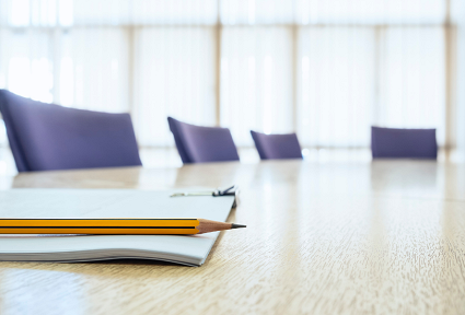empty boardroom with tables and chairs and a pen and pencil on the table