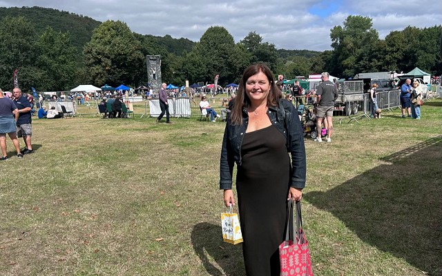 Sioned yn sefyll mewn cae gyda bagiau siopa