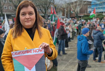 Mae Sioned Williams MS yn dal arwydd sy'n dweud 