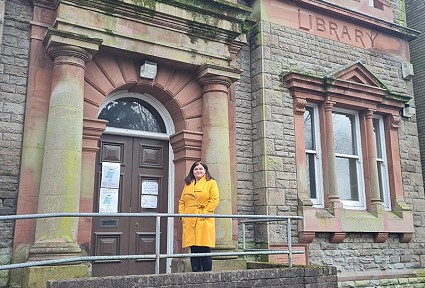 sioned williams wearing a yellow coat standing outside a building