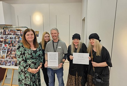 Sioned Williams MS with a group o people holding awards certificates to staff of M&S