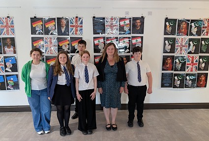 Sioned a disgyblion yr ysgol yn sefyll ar ffurf arddangosfa gelf