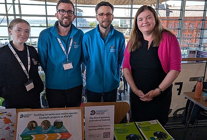Sioned Williams MS stands with representatives from North Wales Wildlife Trust behind a table covered in information about their work. They are stood inside the Senedd.