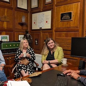 Sioned and Beca with hosts speaking in a wood paneled office