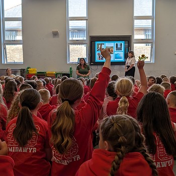 Sioned sitting and speaking to school pupils in an assembly
